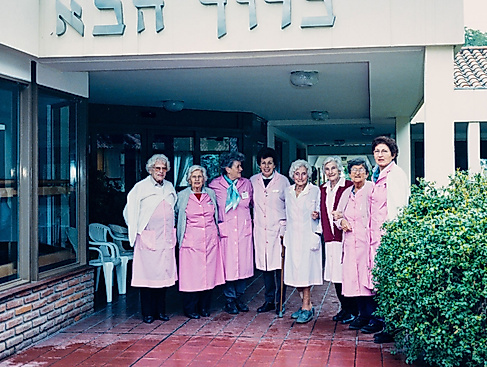 Frauen in rosa Kitteln vor Gebäude