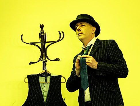 Mann mit Anzug und Hut vor gelbem Hintergrund