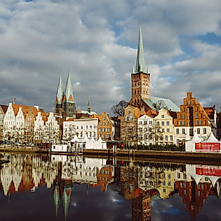 Blick auf Lübecks Altstadt mit Giebelhäusern und Kirchtürmen, gespiegelt im Wasser der Trave