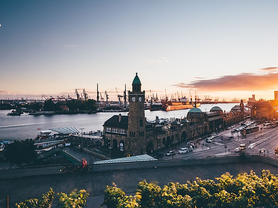Sonnenuntergang über den Landungsbrücken mit Blick auf Uhrturm, Elbe und Hafenkräne im Hintergrund