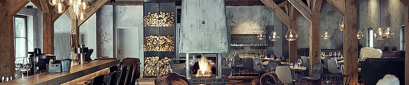 Gemütliches Interieur der HYGGE Brasserie & Bar in Hamburg mit Kamin, Holzdecken und nordischem Design
