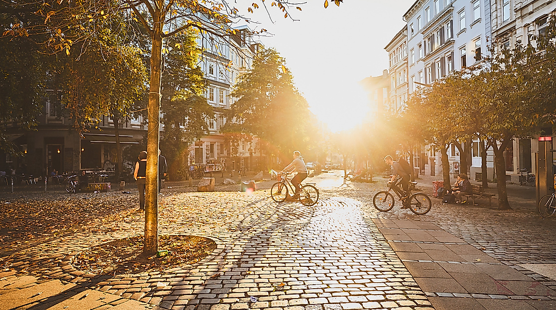 Hein-Köllisch-Platz in Hamburg Ottensen im Gegenlicht der Abendsonne mit Bäumen und Straßencafés