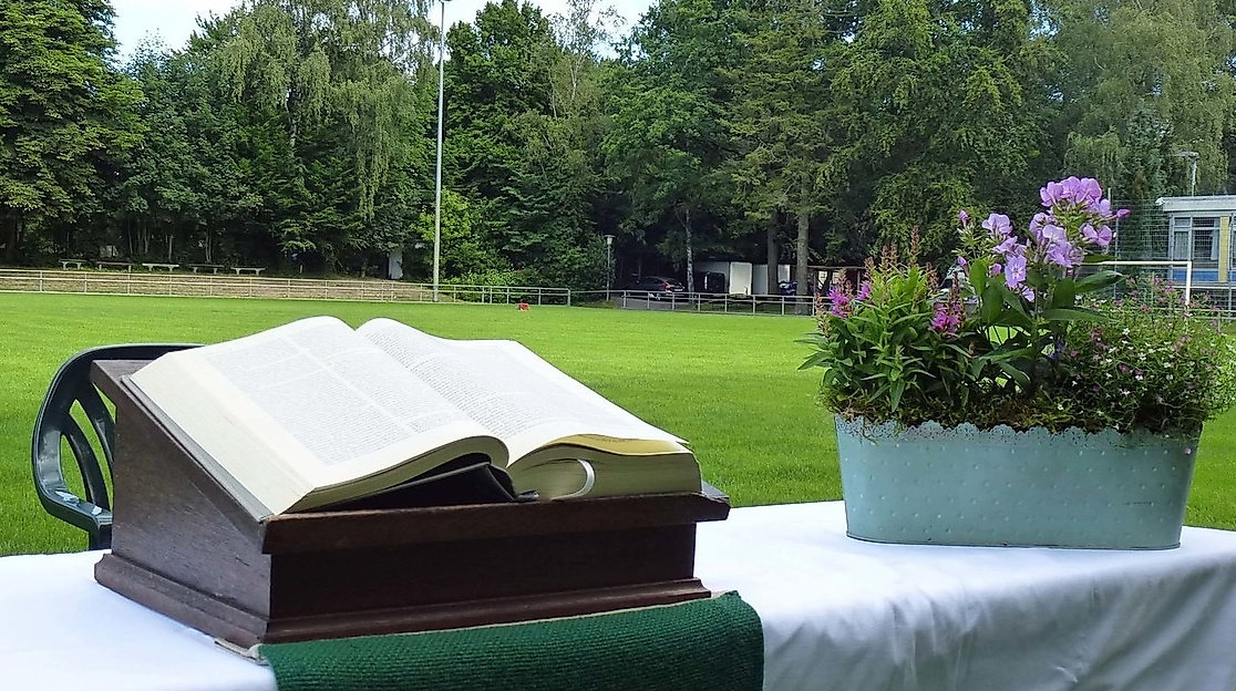 Aufgebauter Altar mit Bibel und Blumenschmuck auf einem Fußballfeld