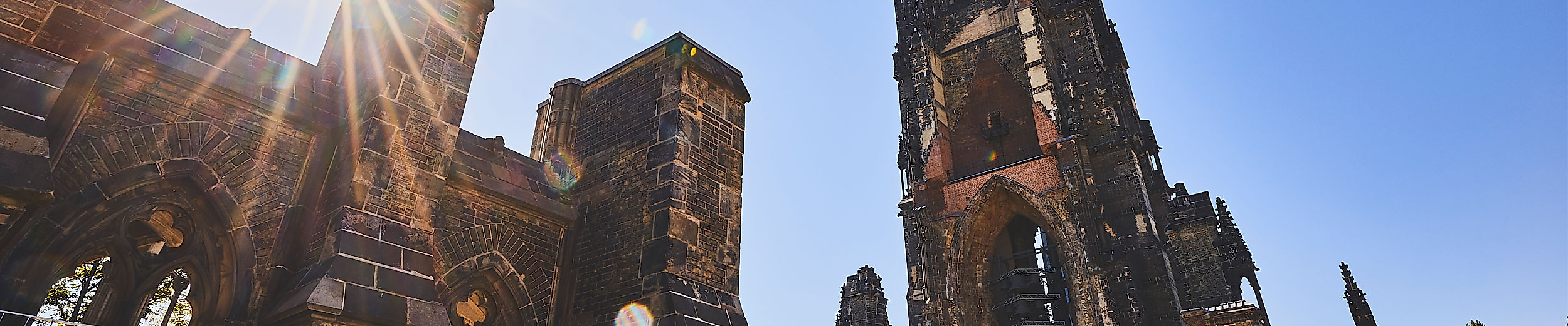 Panorama der Ruine St. Nikolai in Hamburg mit neugotischem Turm, Mahnmal und Sonnenlicht im Mauerwerk