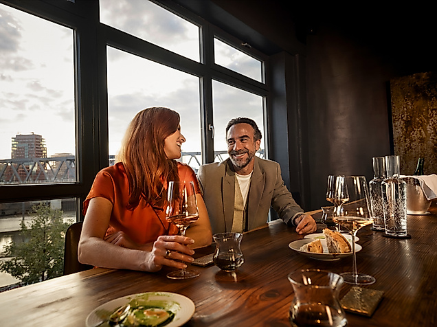 Ein Pärchen sitzt mit einem Glas Wein am Tisch des Restaurants 100/200