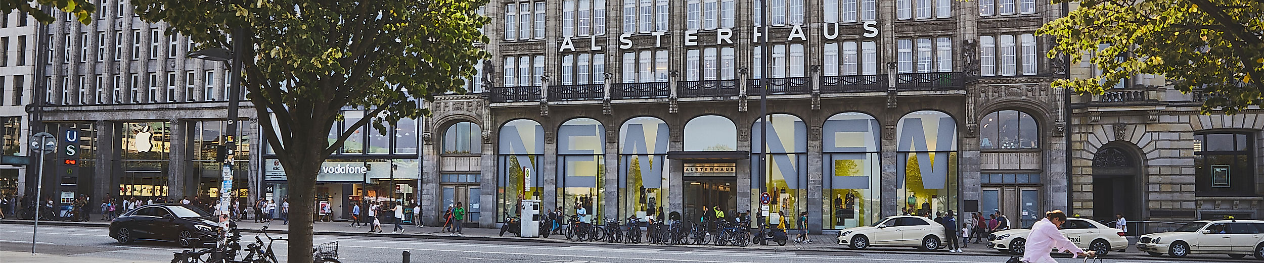 Außenansicht des traditionsreichen Alsterhauses mit Schaufenstern und Flanierenden an der Hamburger Binnenalster