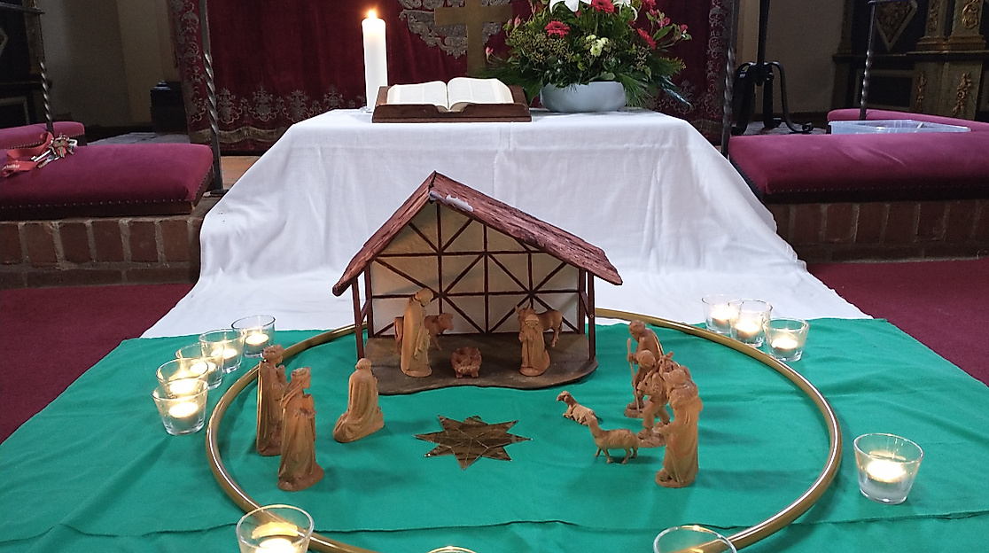 Krippe auf grünem Tuch mit Teelichtern vorm Altar der Schloßkirche