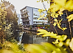 Harburger Theater am Kaufhauskanal in Hamburg, im Sonnenlicht durch Blätter mit Spiegelung im Wasser