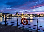 Weihnachtsbaum auf der Alster vor beleuchtetem Jungfernstieg bei blau-violettem Abendhimmel und Rettungsring im Vordergrund