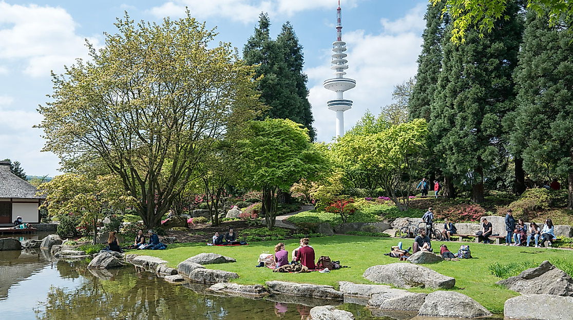 Menschen entspannen im grünen Park Planten un Blomen mit Fernsehturm im Hintergrund