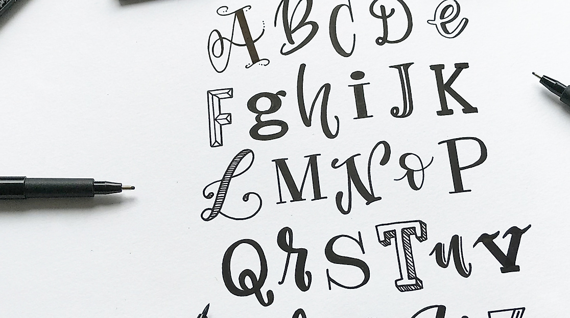 Handgezeichnetes Alphabet in verschiedenen Lettering-Stilen, umgeben von schwarzen Stiften und Radiergummi