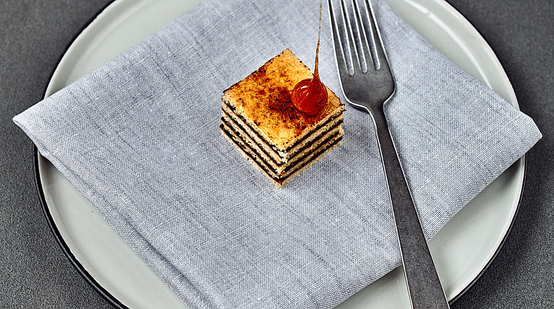 Feines Weihnachtsdessert Wintercake von Björn Juhnke auf Serviette mit Gabel festlich angerichtet auf weißem Teller
