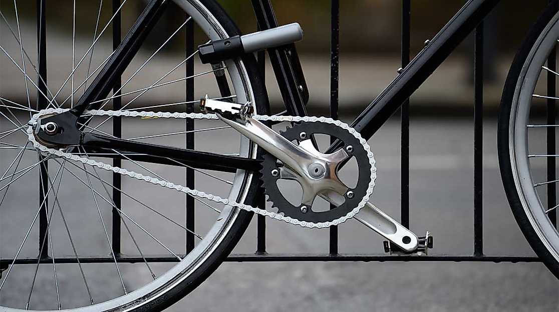Fahrrad mit stabilem Bügelschloss am Rahmen an einem Metallzaun gesichert