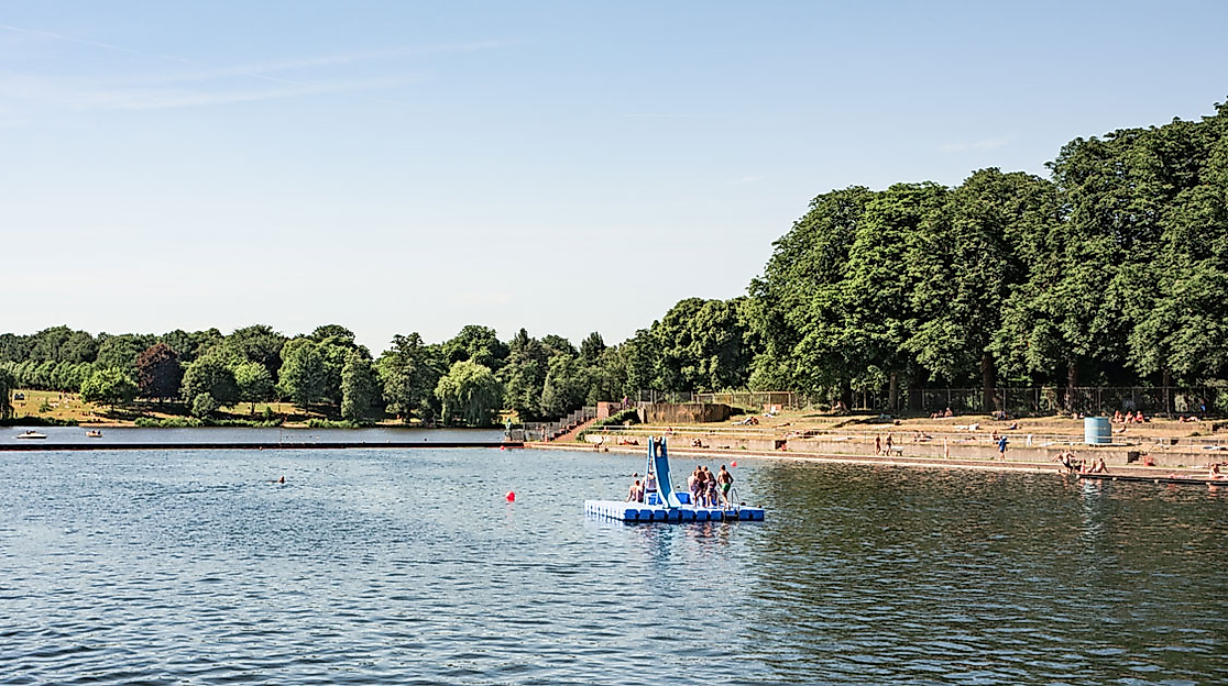 Badegäste und Tretboot im Naturbad am Stadtparksee in Hamburg bei sonnigem Wetter