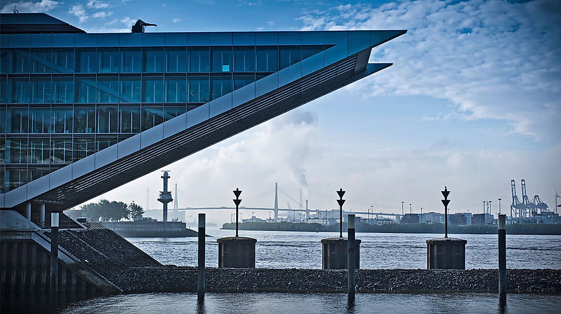 Modernes Bürogebäude Dockland in Hamburg mit markanter Glasfassade und Blick auf die Elbe bei Dämmerung.