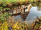Spiegelung des Bergedorfer Schlosses im Wasser, umgeben von herbstlicher Ufervegetation in Hamburg-Bergedorf