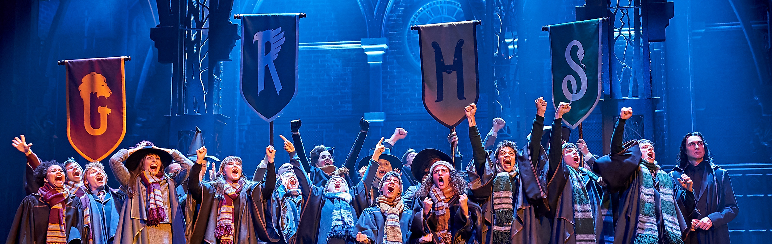 Bühnenensemble jubelt unter Hogwarts-Bannern bei der Harry-Potter-Show im Mehr! Theater Hamburg.