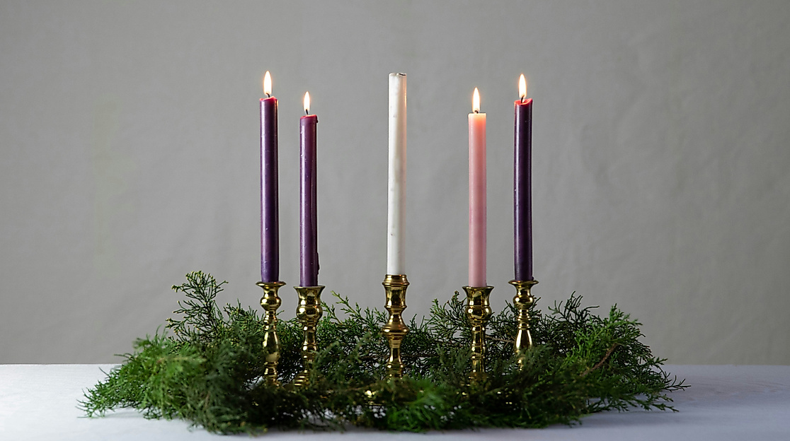 vier Kerzen brennen in einem Gesteck