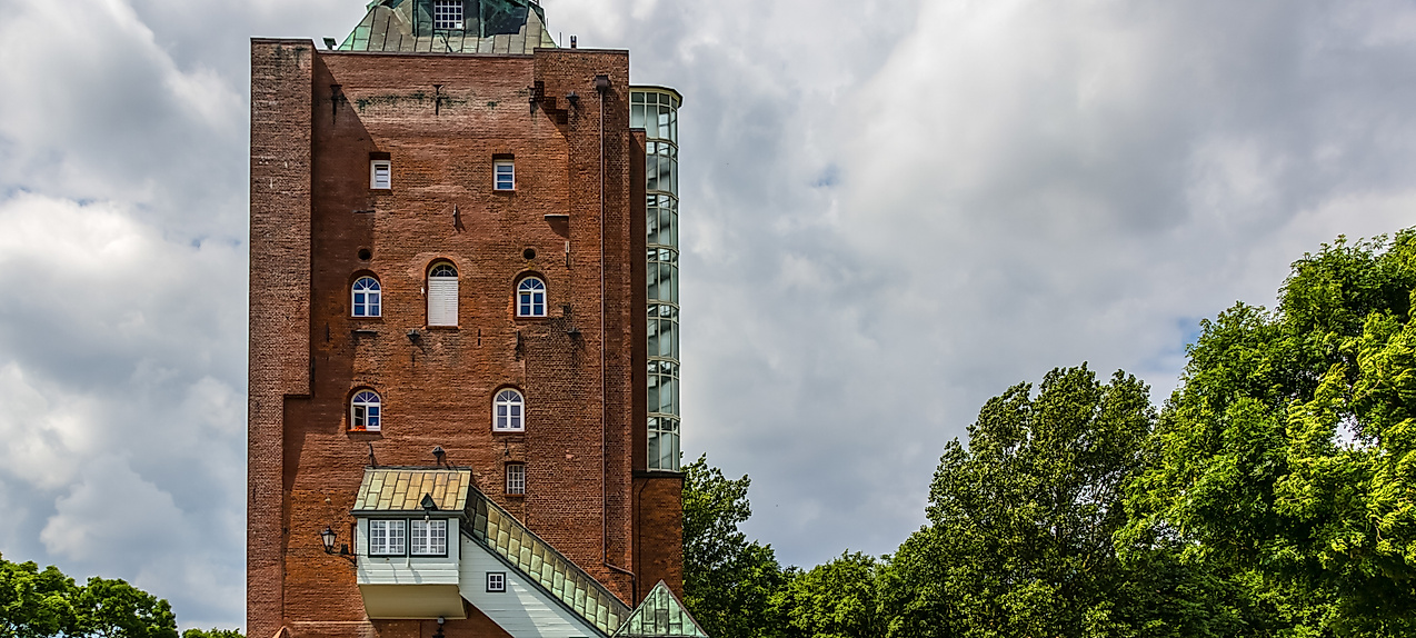 Backsteinleuchtturm auf Neuwerk mit Besucherzugang, umgeben von Bäumen 