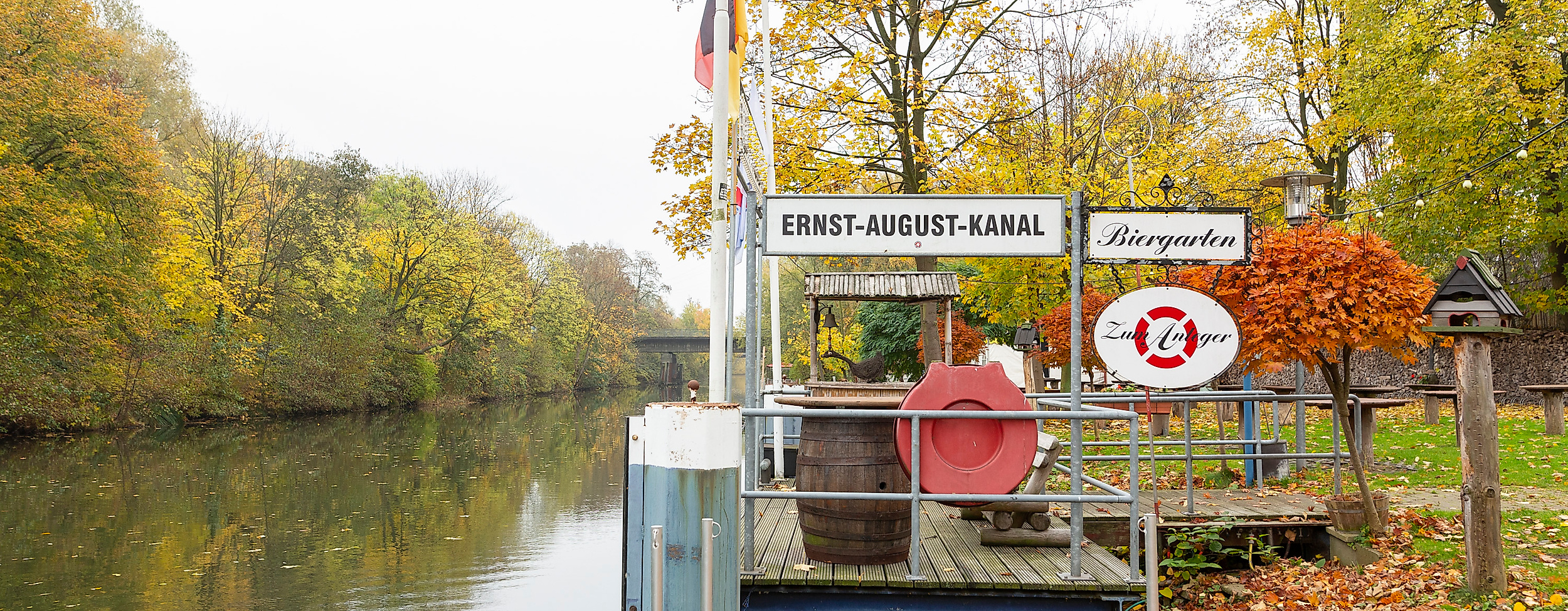 Anleger im Biergarten Zum Anleger am Harburger Kanal, umgeben von herbstlich gefärbten Bäumen
