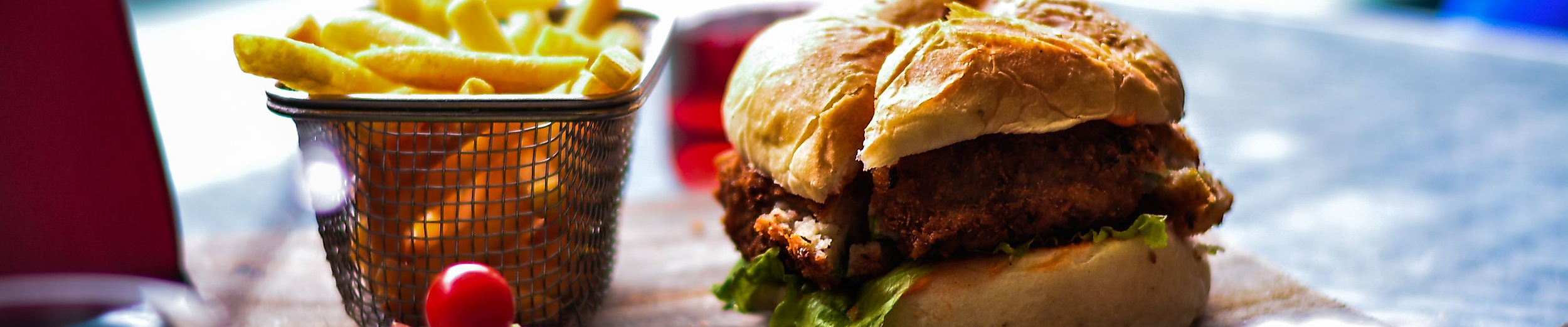 Frischer Burger mit Pommes auf Holzbrett, serviert in Hamburger Restaurantambiente