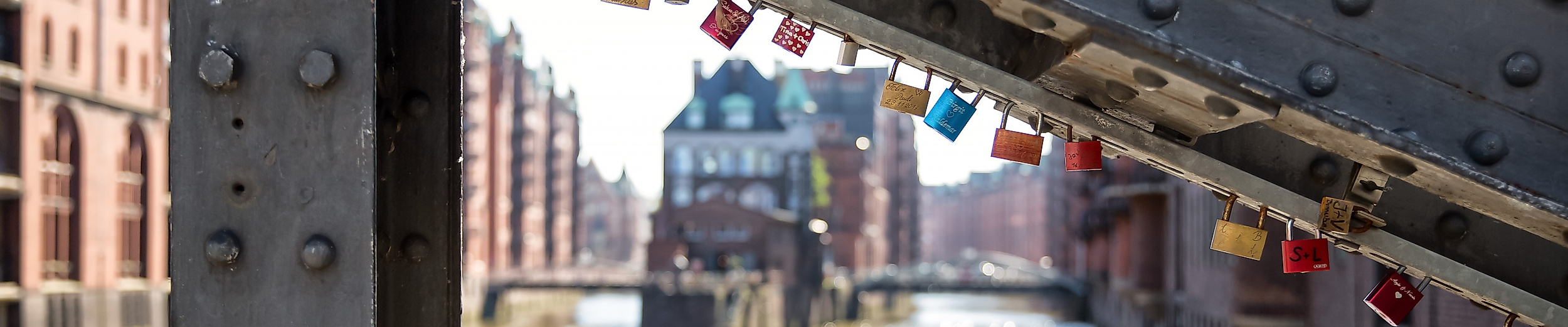 Liebesschlösser an Brücke in der Speicherstadt mit Blick auf das Wasserschloss in Hamburg