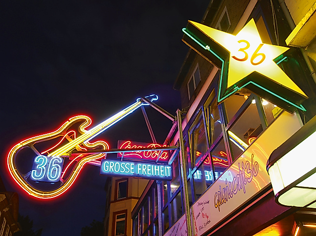 Leuchtende Gitarren- und Sternreklame bei Nacht am Eingang zur Großen Freiheit auf der Reeperbahn in St. Pauli