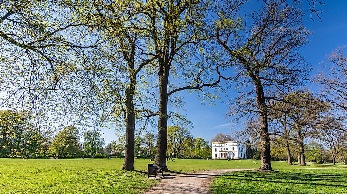 Weitläufige Wiese mit Bäumen im Jenischpark und Blick auf das klassizistische Jenisch-Haus in Hamburg