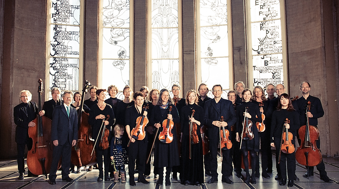 Orchesterfoto vor verzierten Fenstern