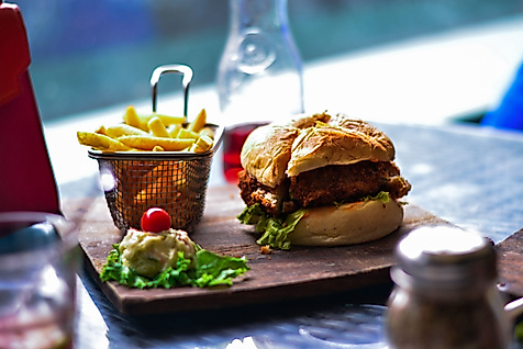Frischer Burger mit Pommes auf Holzbrett, serviert in Hamburger Restaurantambiente