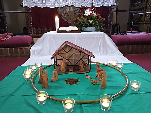 Krippe auf grünem Tuch mit Teelichtern vorm Altar der Schloßkirche