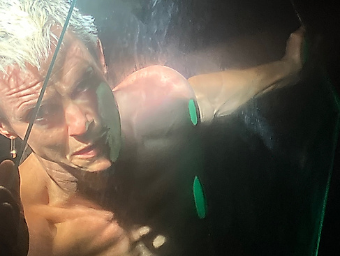 Ausschnitt aus der Perfoprmance Incontrovertible Being von Cassils. Eine Person hält eine Glasscheibe vor sein Gesicht.