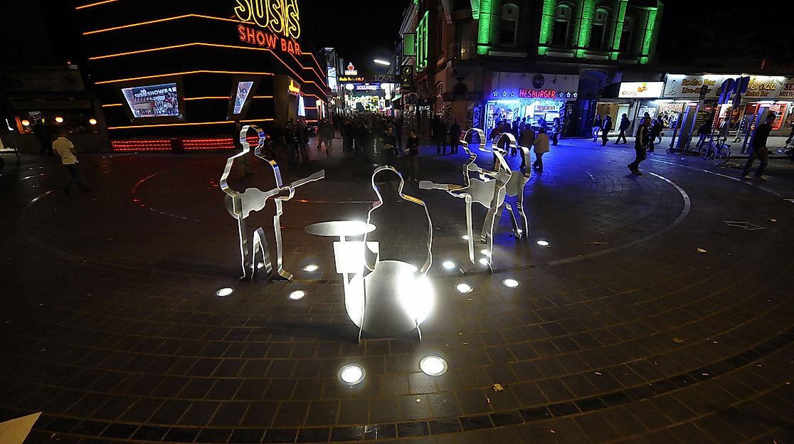 Beleuchtetes Beatles-Platz-Denkmal auf der Reeperbahn bei Nacht mit umliegenden Clubs