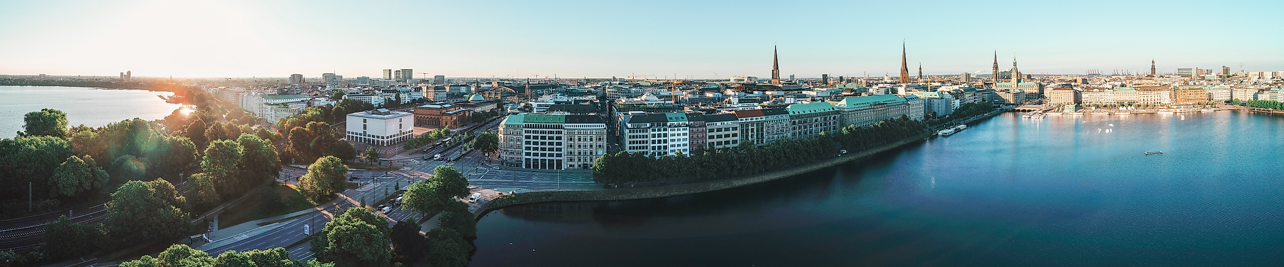 Panorama der Binnenalster bei Sonnenaufgang mit Blick auf Hamburgs Innenstadt und glitzerndem Wasser