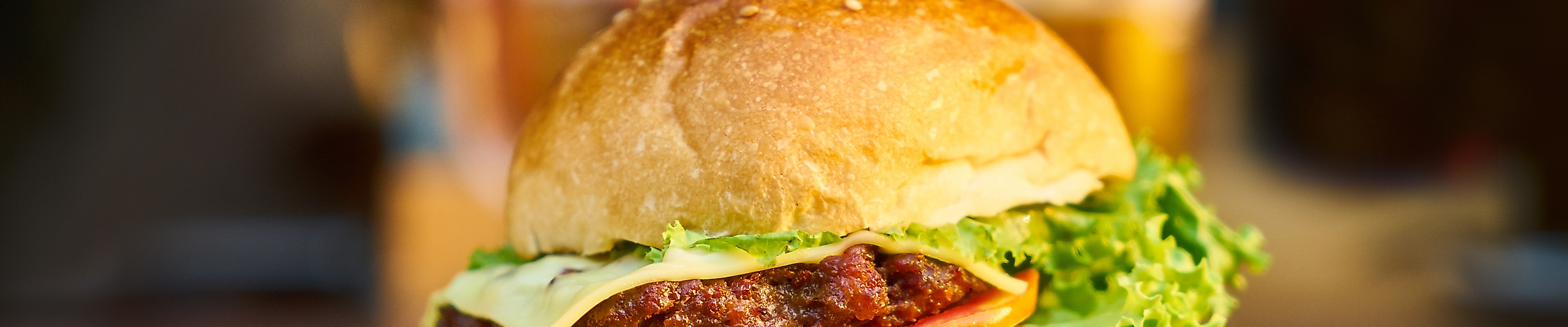 Saftiger Cheeseburger mit Salat und Tomate, serviert mit Pommes auf dunklem Tisch