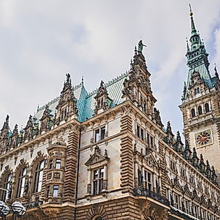 Hamburger Rathaus mit Türmen und Fassade aus schräger Perspektive vor hellem Himmel