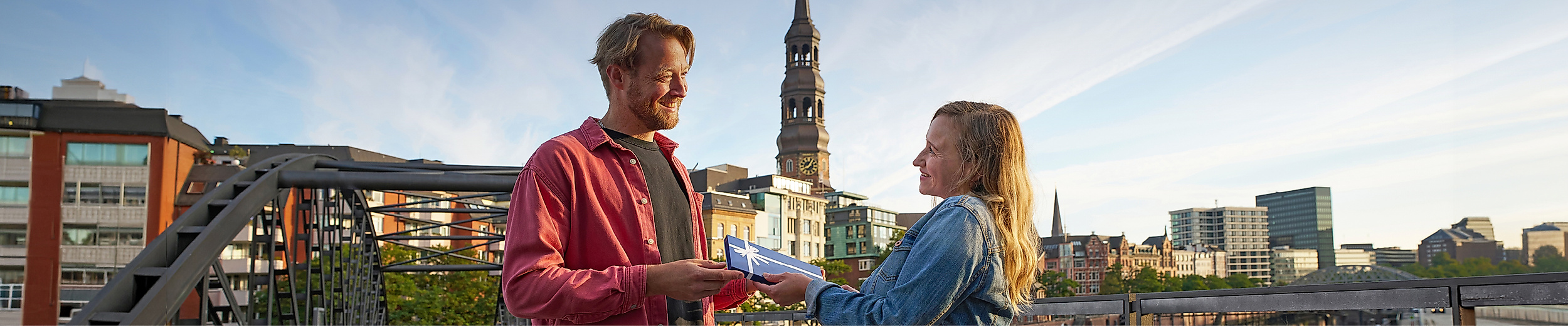 Ein Mann überreicht einer Frau einen Hamburg Gutschein