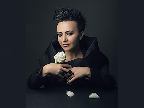 Amira Medunjanin schaut bedächtig auf eine weiße Rose in ihrer Hand.