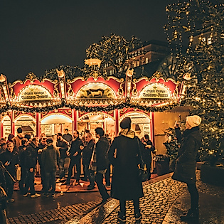 Illuminated carousel and festively decorated Christmas tree at the Christmas market at night
