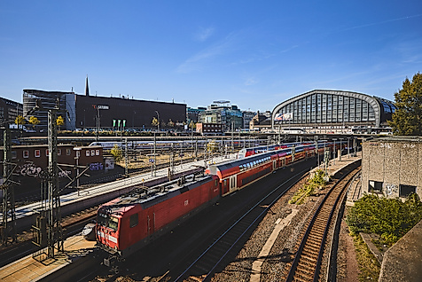 Regionalzug der DB vor dem Hamburger Hauptbahnhof bei Sonnenschein und klarem Himmel.