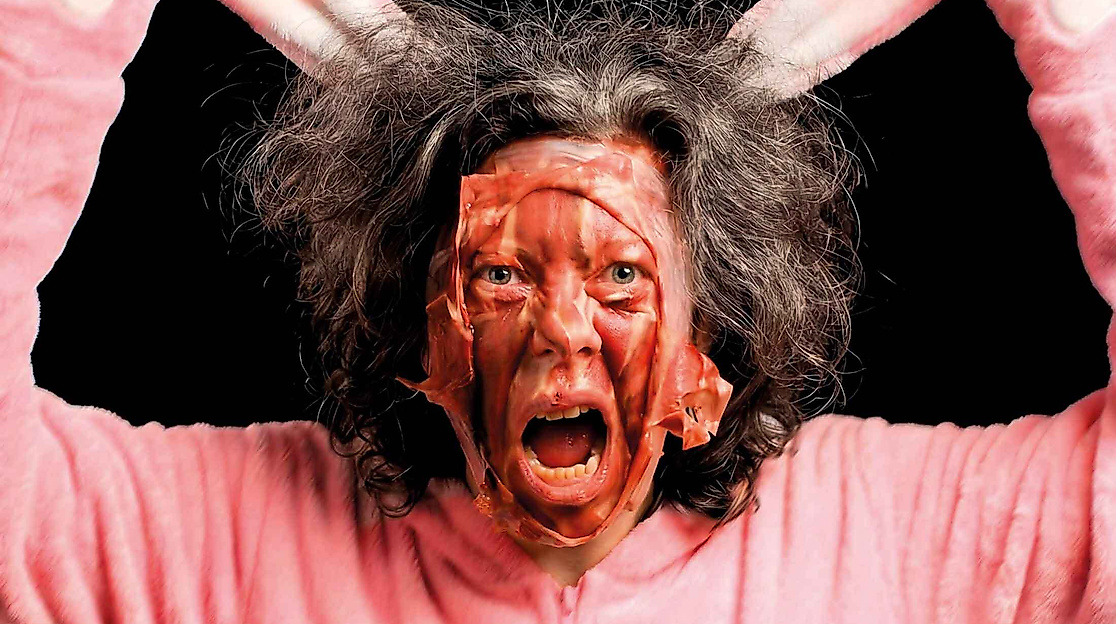 Eine Person mit zerzausten Haaren trägt ein rosa Hasenkostüm.