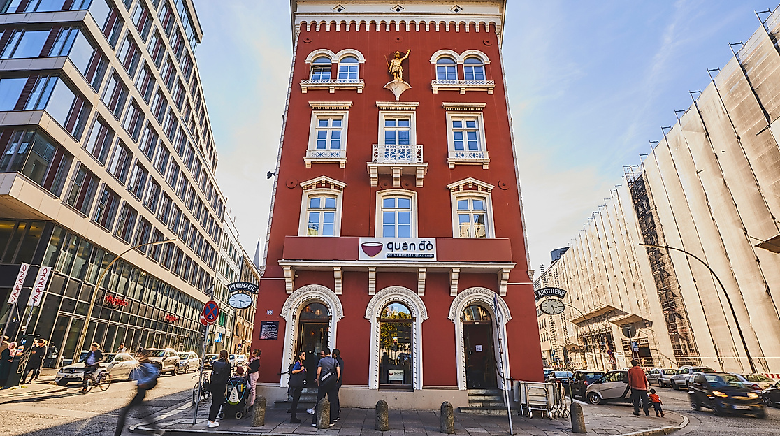 Frontalansicht des roten Altbaus mit dem vietnamesischen Restaurant Quan Do in moderner Umgebung