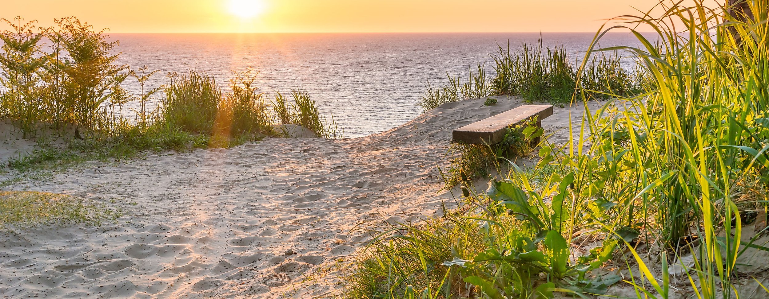 Sonnenuntergang über der Ostsee mit Bank am Küstenpfad – ruhiger Ausblick aufs Meer ab Hamburg