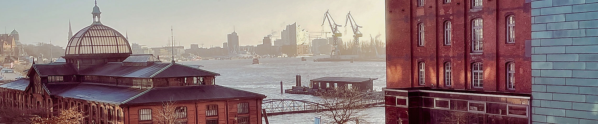 Blick auf das GINN Hotel Hamburg Elbspeicher, die Fischauktionshalle und den Hafen bei Sonnenaufgang