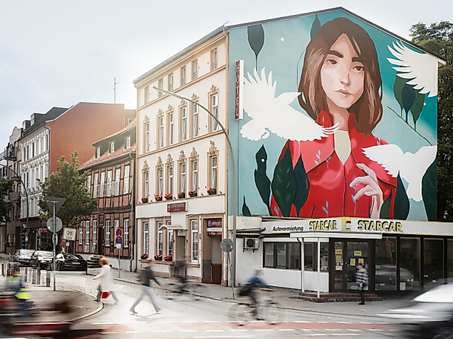 Großes Wandbild mit stilisierter Frauenfigur und Pflanzenmotiven an Hausfassade in Hamburger Wohnstraße