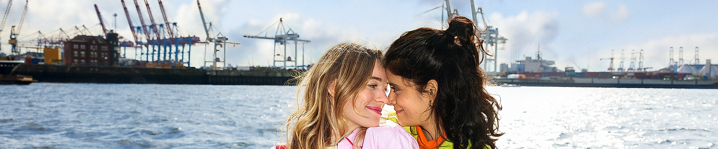 Zwei der LGBTQIA+ Community angehörige Frauen sitzen am Hamburger Hafen