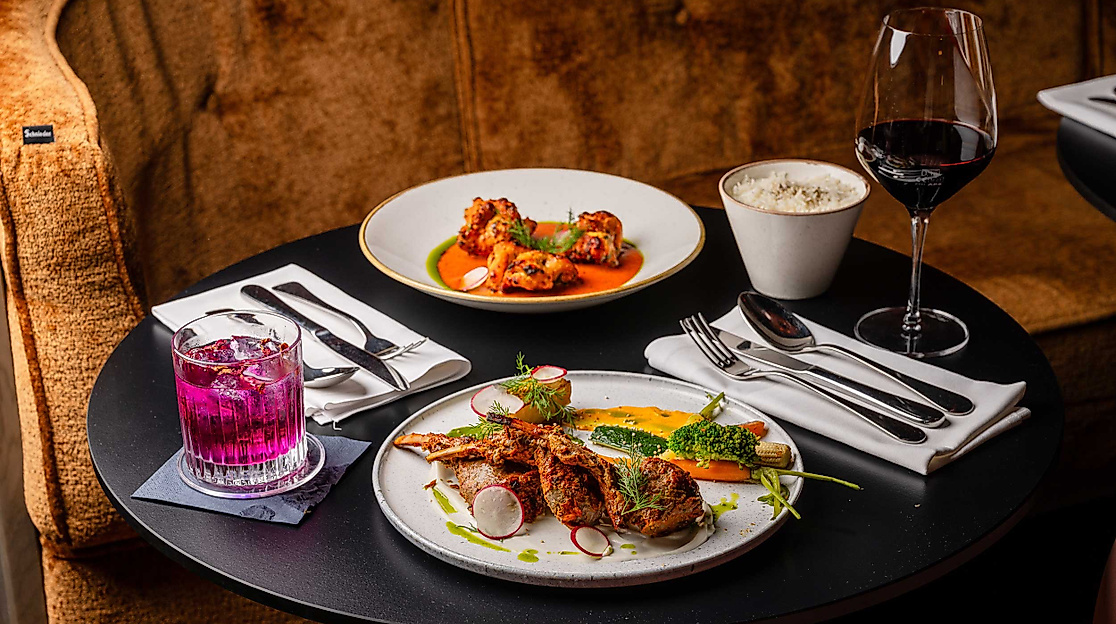 Stilvoll gedeckter Tisch mit modern interpretierten Gerichten im Restaurant Cardamom im Westfield Hamburg Überseequartier.