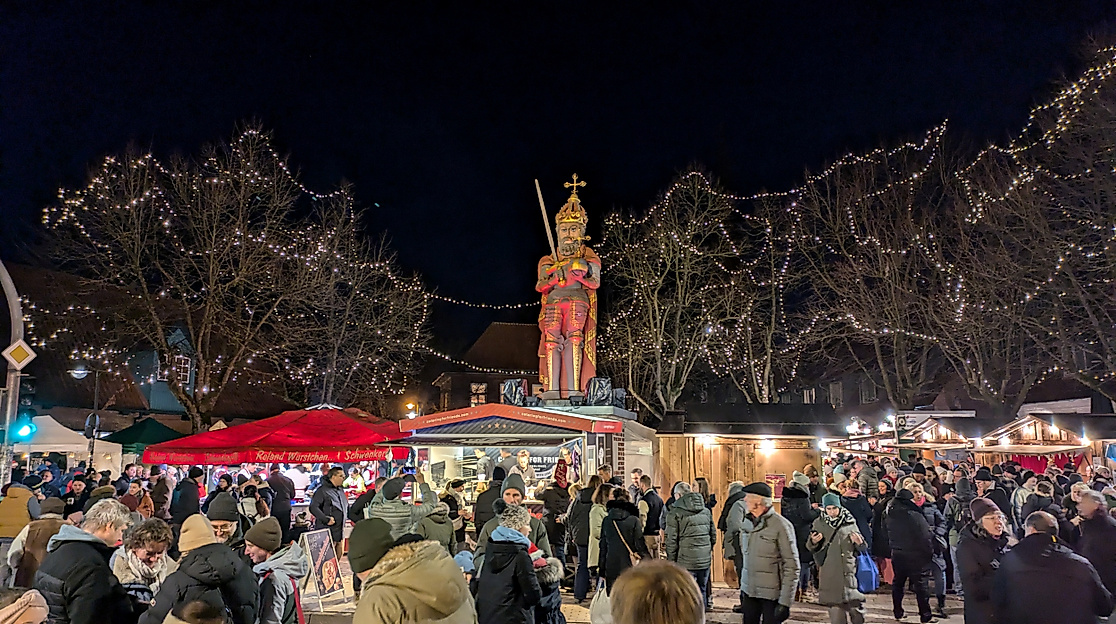 Menschenmenge beim Wedeler Weihnachtsmarkt am Roland mit Weihnachtsbeleuchtung und Ständen