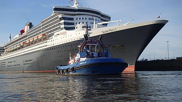 QM2 mit Schlepper vorne - Foto Hans-Jürgen Müller
