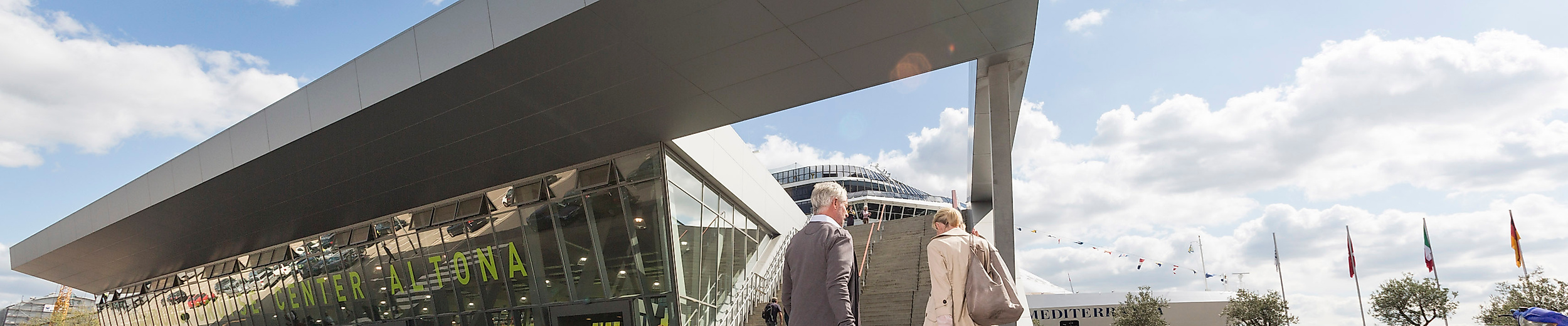 Reisender mit Rollkoffern vor dem modernen Terminalgebäude des Cruise Center Altona in Hamburg